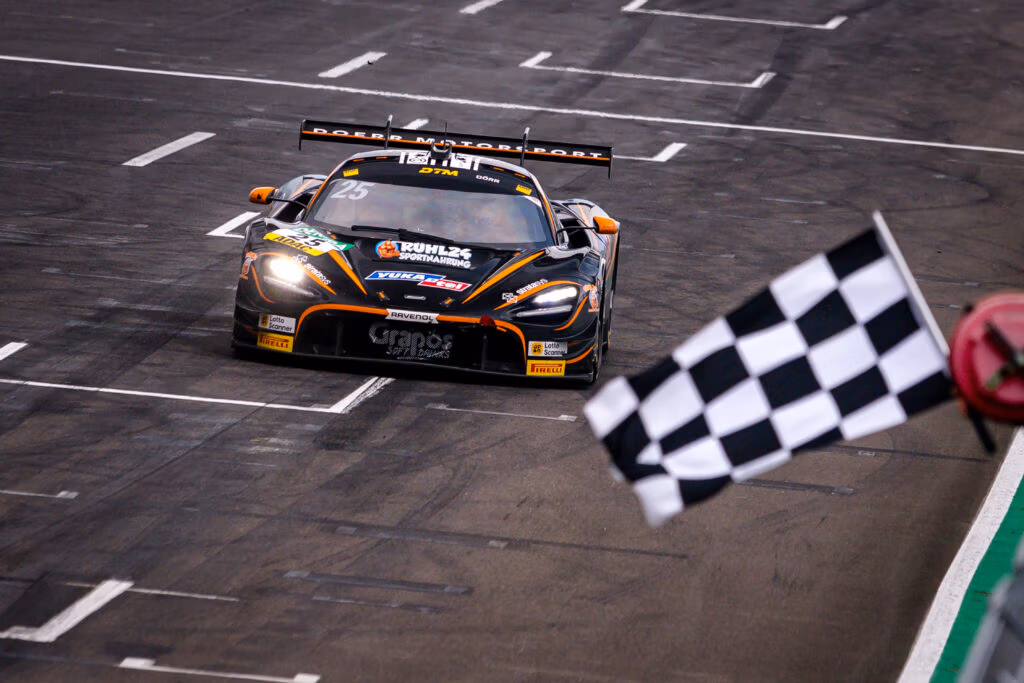 Der McLaren von Ben Dörr fährt an einer karierten Flagge vorbei.