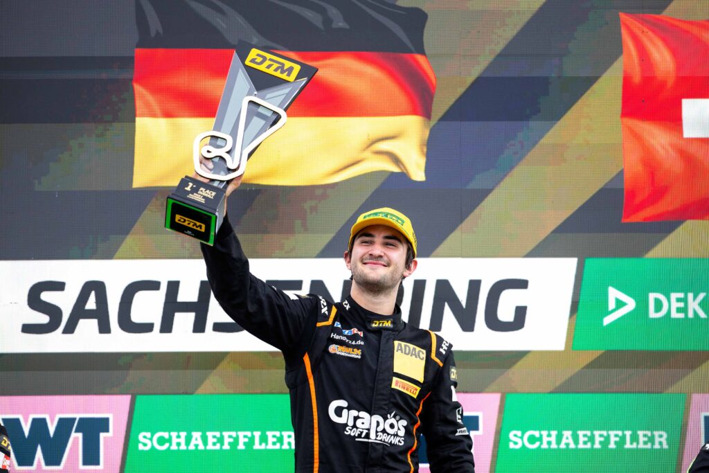 Ben Dörr hält am Sachsenring lächelnd eine DTM-Trophäe in die Höhe.